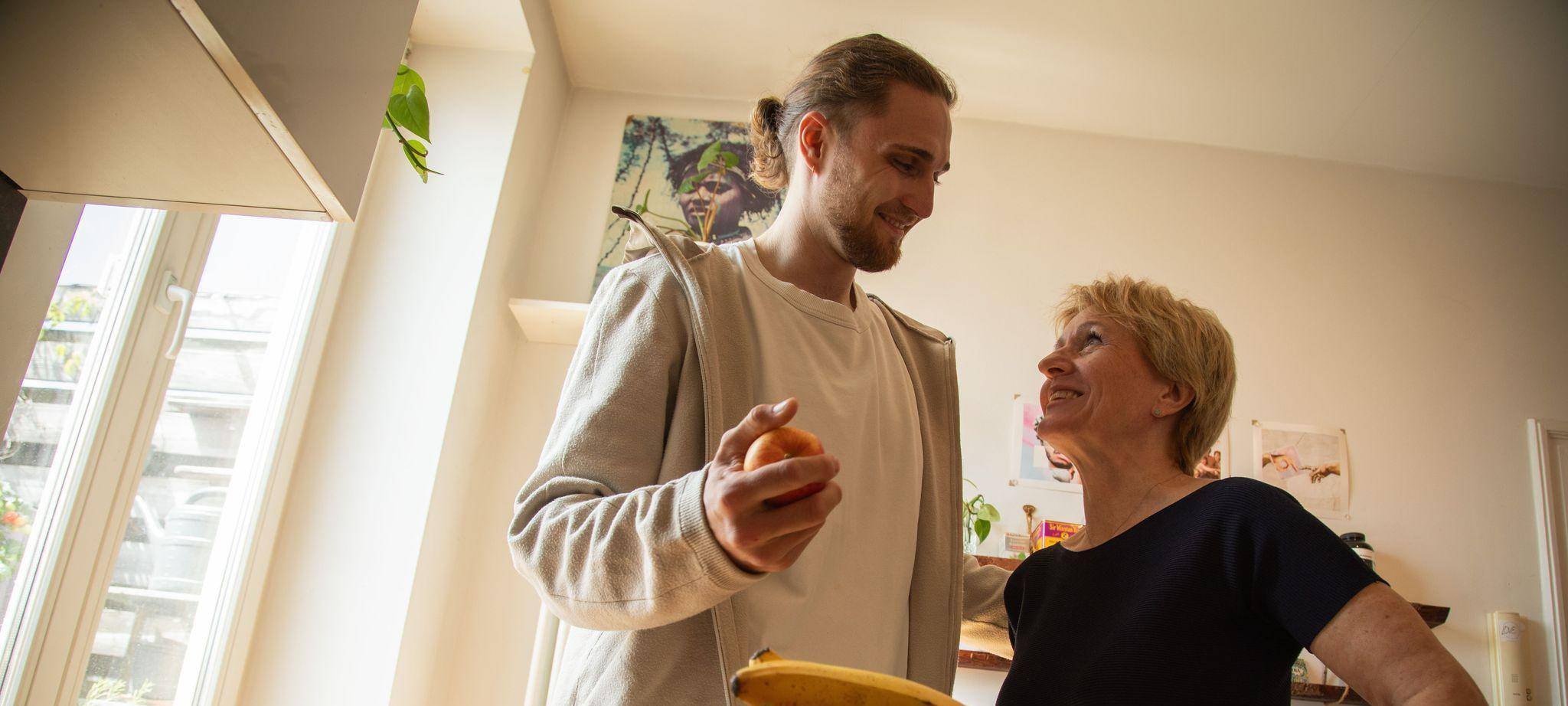 Ein junger Mann hilft einer älteren Frau in der Küche