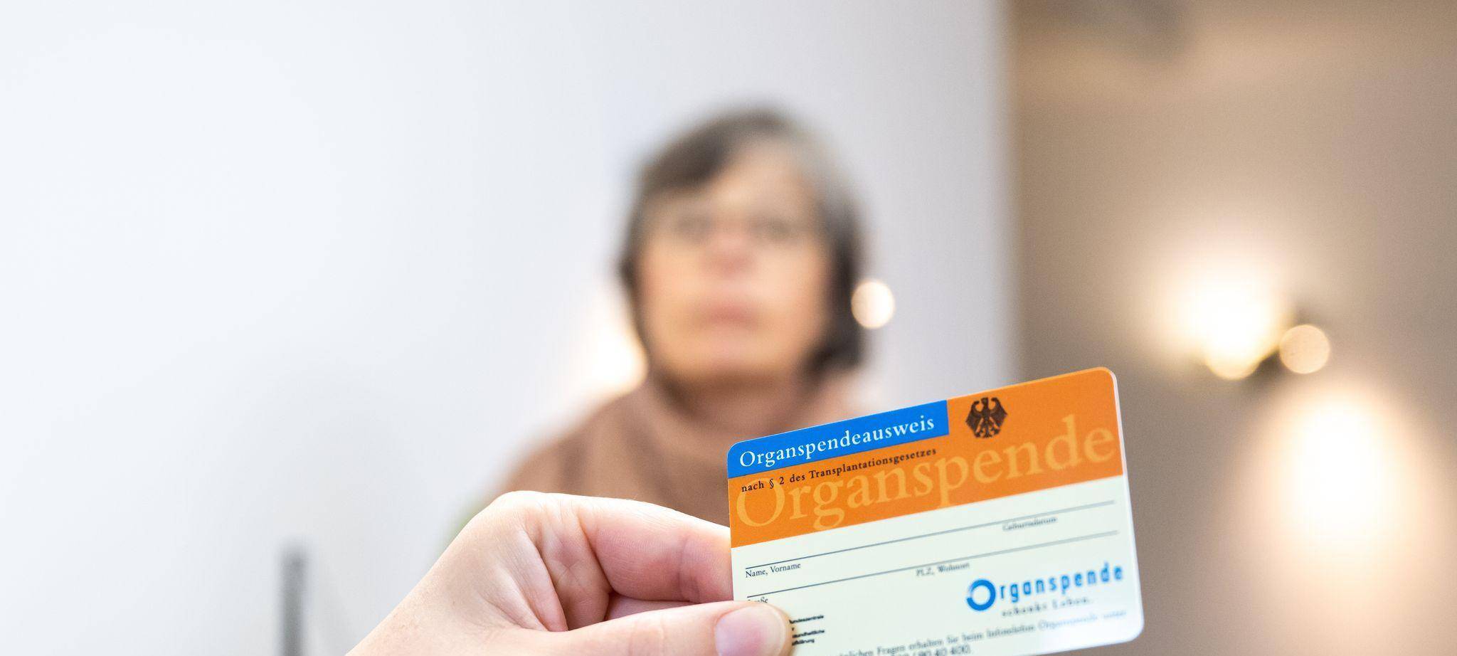 Person hält in einer Arztpraxis einen Organspendeausweis